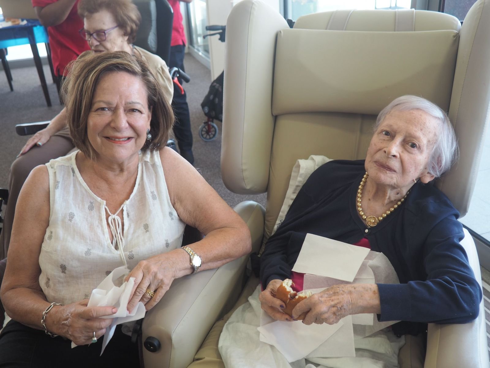 Two senior women chatting in an aged care lounge